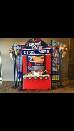 an arcade machine with some balloons on the top and one ticket zone sign above it