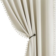 a white curtain with pom poms hanging from it's side and the curtains are closed