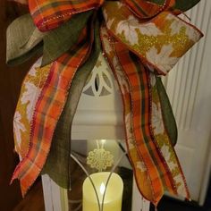 an orange and green wreath with a lit candle on it's front door hanger