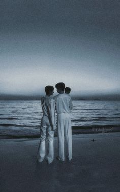 three people standing on the beach looking out at the ocean