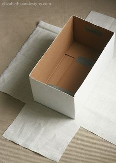 an open cardboard box sitting on top of a white piece of cloth next to a pair of scissors