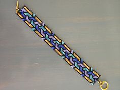 a beaded bracelet on a wooden table with a gold keychain hanging from it