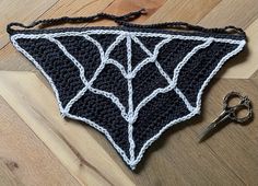 a crocheted black and white triangle with a pair of scissors