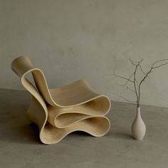 a white vase sitting next to a set of three wooden chairs on top of a cement floor