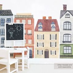 a child's desk and chair in front of a wall with houses painted on it