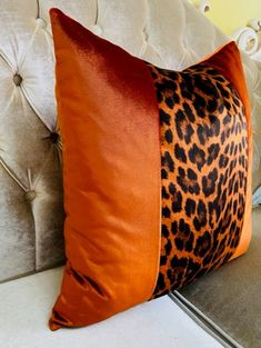 an orange and black pillow sitting on top of a couch