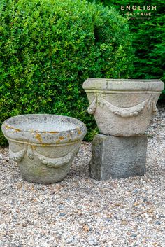 two cement planters sitting on top of gravel