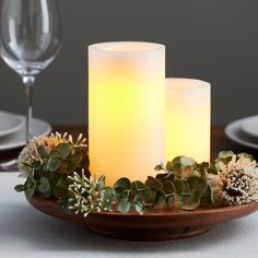 two lit candles sitting on top of a wooden plate