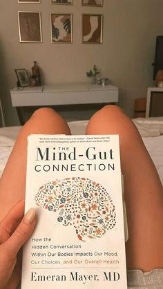 someone is reading a book about mind - gutt connection on the bed in their bedroom