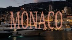 the word monaco spelled out in front of a large cityscape with boats docked at night