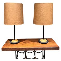 two lamps sitting on top of a wooden table next to a lamp holder with one light on it