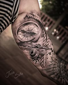 a man's arm with a compass tattoo on it