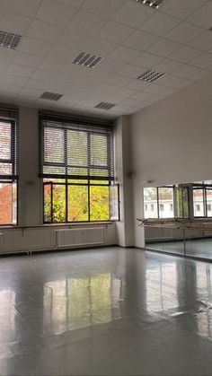 an empty room with windows and benches in the middle is seen from across the room