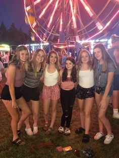 some girls are standing in front of a ferris wheel