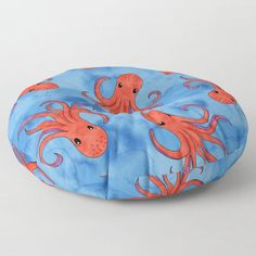 an octopus and squid pattern on a blue floor pillow with coral colored tentacles in the middle