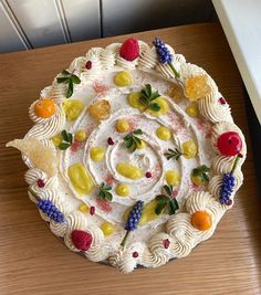 a cake decorated with fruit and berries on top of a wooden table