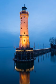 a light house sitting on top of a pier next to the ocean at night time