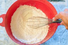 a person mixing flour in a red bowl