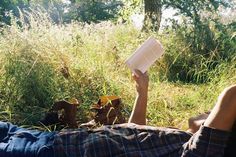 a man laying in the grass reading a book