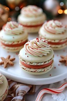 several decorated cookies on a white platter with candy canes and decorations in the background