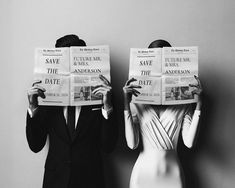 two people in suits are holding newspapers over their heads while standing next to each other