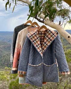 two coats hanging from a tree in the mountains