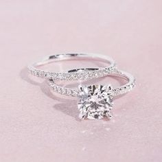 an engagement ring with a diamond on top and two bands around the band, in white gold