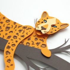 a paper cut out of a cheetah sitting on top of a tree branch