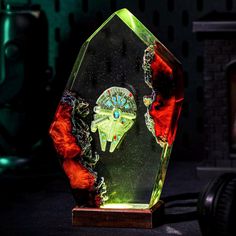 a glass award with an image of a spaceship in the center on a wooden base