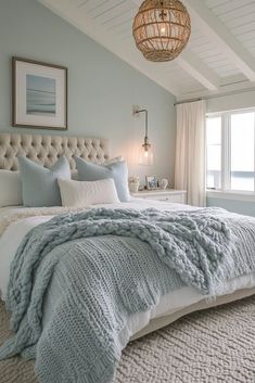 a large bed sitting under a window next to a chandelier in a bedroom