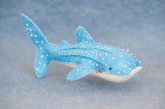 a blue toy shark with white dots on it's body and tail, sitting on a gray surface