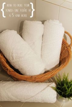 towels in a wicker basket sitting on a tiled wall next to a potted plant