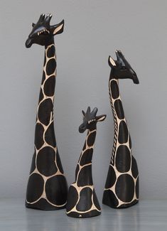 three ceramic giraffes standing next to each other in front of a gray wall