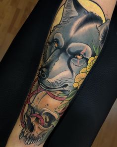 a man with a wolf tattoo on his arm holding a human skull and flowers in front of him