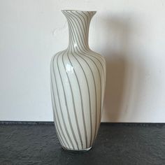 a white vase sitting on top of a black table