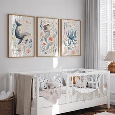 a baby's room with two paintings on the wall and a white crib