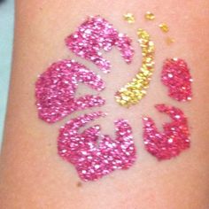 the word love spelled out in glitter on someone's leg with gold and pink colors