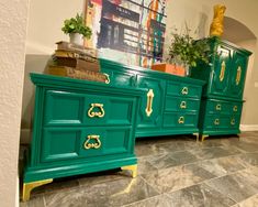 two green dressers with gold handles on each side and one has a plant in the middle