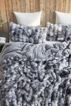 a bed covered in gray and white fluffy blankets