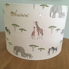 a lamp shade with giraffes and elephants on it