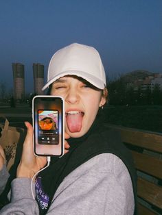 a woman sticking out her tongue while holding up a cell phone