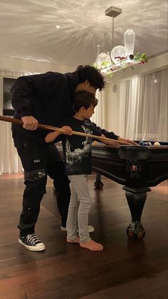 a man teaching a child how to play pool