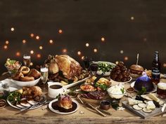 a table full of food and drinks with lights in the background