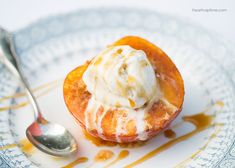 a plate topped with an apple covered in ice cream and caramel sauce next to a spoon