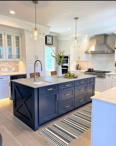 a large kitchen with an island in the middle and two lights hanging from the ceiling