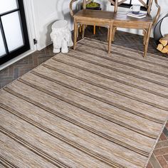 a room with a chair, table and rug on the floor in front of it