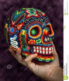 a hand holding up a colorful skull