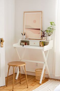 a white desk with a plant on it and a chair next to it in front of a door