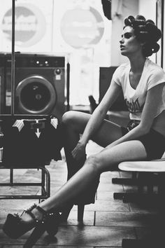 a black and white photo of a woman sitting on a bench with her legs crossed