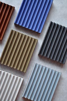 five different colors of corrugated roofing sheets on a table top with one laying down